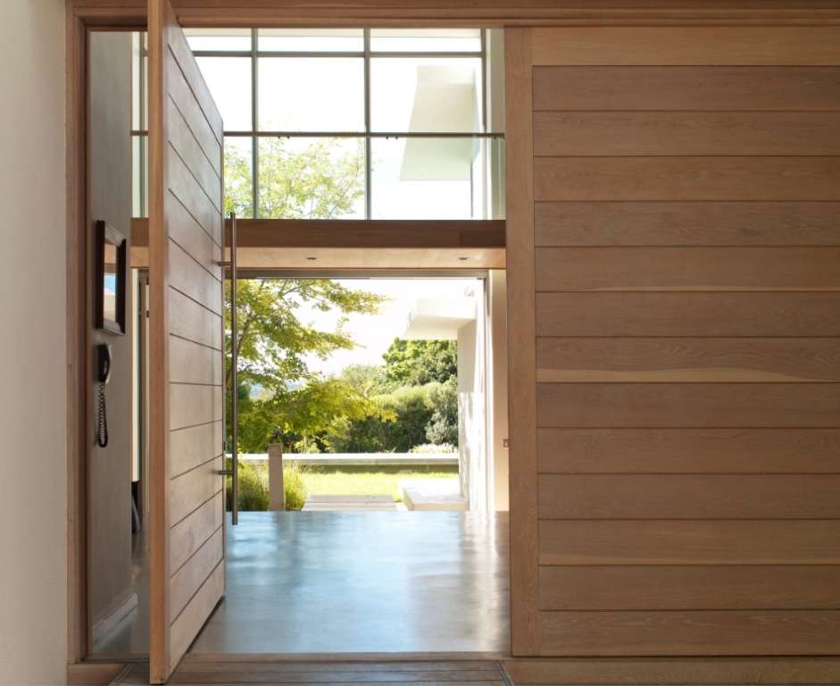 Light wood planked wall and door that is swung open to the large porch